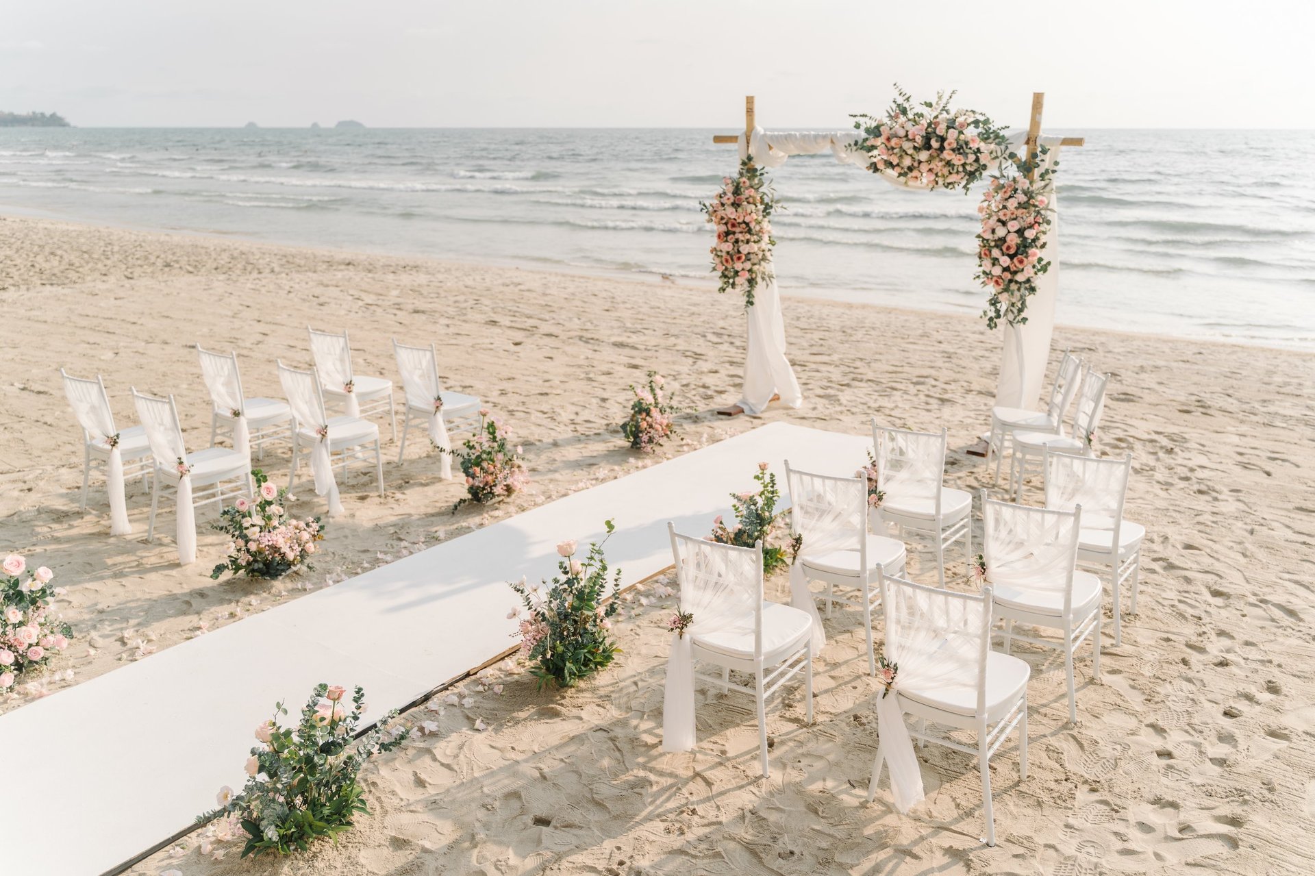 Boda destino en la playa de México con arco floral y océano cristalino